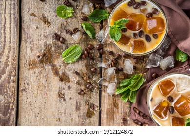 Cold Summer Coffee, Latte, Frappe, Frappuccino. Coffee Iced Cocktail Drink With Frozen Coffee Ice Cubes, Milk Or Non-dairy Milk And Mint Leaves. Wooden Background Copy Space