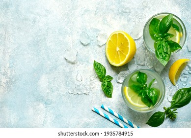 Cold summer lemonade with basil and lemon in a glass on a light blue slate, stone or concrete background. Top view with copy space.