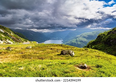 Cold Summer In Norway. Traveling By Camper On Road 520. Ice Lake Surrounded By Green Mountains. Heavy Gray Clouds Cover The Sky