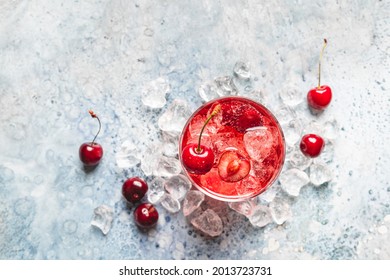 Cold sweet cherries lemonade with fresh sweet cherry and ice on white blue background, top view