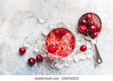 Cold sweet cherries lemonade with fresh sweet cherry and ice on white blue background, top view