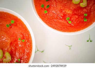 Cold Tomato Soup Gazpacho with basil, microgreens and celery in white cups on a light table. View from above. High quality photo - Powered by Shutterstock