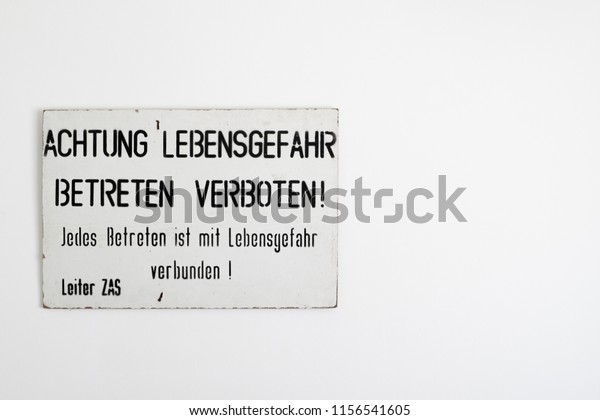 Cold
War East - West German border / Berlin Wall warning sign on a white
wall with copy space. English translation: Warning danger to life.
Entry prohibited. Every ingress is life
threatening.