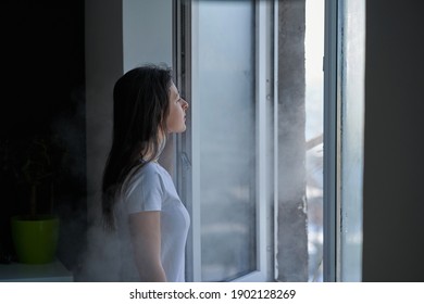 Cold Winter Weather. Woman Step To Window, Open It And Frosty Air Rushes From Outside Through Open Windows To Apartment. Airing Housing In Cold Winter.