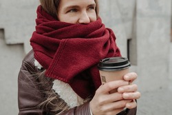 Cold Woman Standing Outside Wrapped In A Scarf With Coffee Cup In Her Hands, Trying To Get Warm. Cropped.
