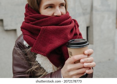 Cold Woman Standing Outside Wrapped In A Scarf With Coffee Cup In Her Hands, Trying To Get Warm. Cropped.