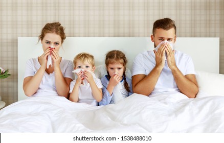 Colds And Viral Diseases. Family With Runny Nose And Fever In Bed At Home
