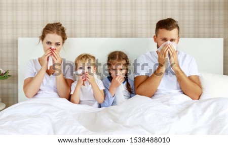 colds and viral diseases. family with runny nose and fever in bed at home
