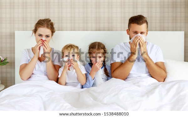 colds and viral diseases. family with runny nose\
and fever in bed at\
home\
