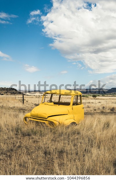 Colesberg, South Africa, 20\
February, 2018 - Yellow vintage car wreck on a beautiful field in\
Africa