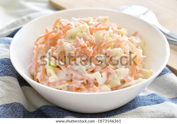 Coleslaw\
salad with carrot and cabbage on a white\
bowl.
