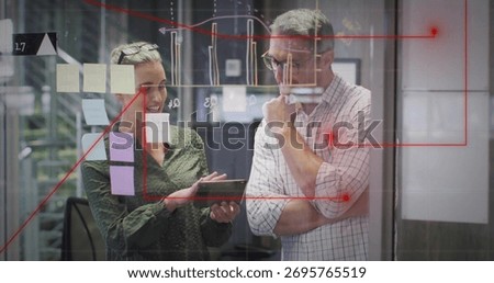 Collaborating colleagues analyzing data behind glass partition with tablet post-its and charts. Collaboration, brainstorming, data analysis, teamwork, innovation, modern office, project management