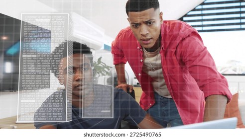 Collaborating two men in navy tee, red shirt reviewing laptop screen at office, with binary overlay. Teamwork, computer, desk, coworking, workplace, modern, daylight