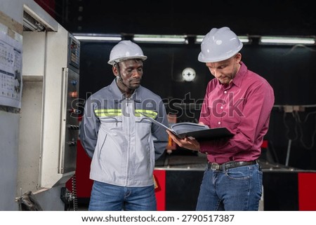 Collaboration between engineers and technicians in industrial setting factory floor documentation review professional environment close-up perspective