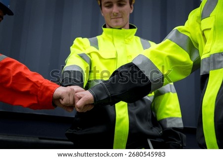 Collaboration and teamwork are essential in workplace, as shown by team workers in bright safety gear engaging in fist bump. This moment symbolizes unity and mutual respect.