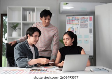 Collaborative Design Session and Insight Sharing. Team members discuss design elements on a laptop while brainstorming.