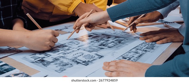 A collaborative design session where a diverse group engages with sketches and blueprints on a table, showcasing teamwork and innovative planning in an inspiring workspace. SACTR