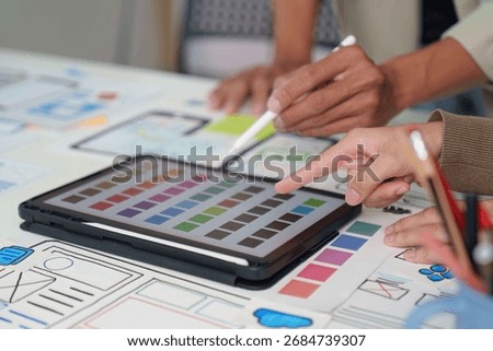 Collaborative Design. Team brainstorming on digital interface mockups and color palettes.