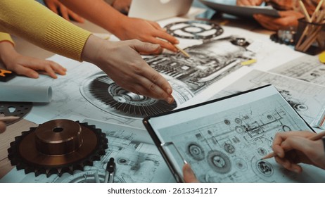 A collaborative group of engineers explores mechanical design ideas on drawings and blueprints, surrounded by tools, enhancing creativity and innovation in their workspace. SACTR
