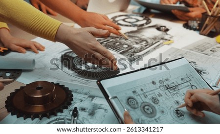 A collaborative group of engineers explores mechanical design ideas on drawings and blueprints, surrounded by tools, enhancing creativity and innovation in their workspace. SACTR