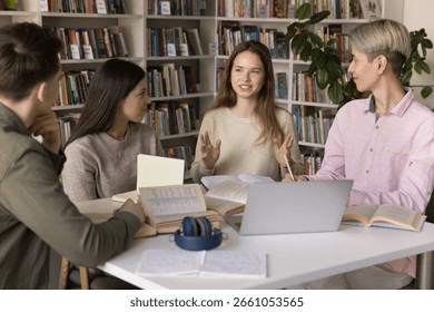 Collaborative learning. Confident young high school girl student speak on group study session in campus library share idea with diverse groupmates engage peers in active discussion for problem solving