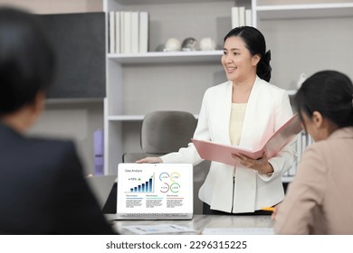 Collaborative process of professional businesspeople using computer and going over on meeting presentation with growth analysis, charts, statistics and data at office meeting concept.