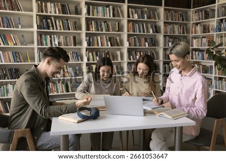 Collaborative research and note taking. Busy young diverse students zoomers gather around table in classroom focused on writing up information using paper online literature prepare academic assignment
