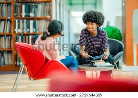 Collaborative study moment with students using tablet in library lounge showing academic teamwork self learning routine education space.