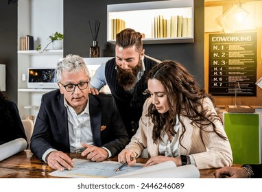 Collaborative team analyzing strategy in modern coworking space. Experienced leader guides young professionals through project details. A blend of generational knowledge and diverse insights.