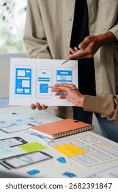 Collaborative UI UX Design. Team analyzing mobile app wireframes and layouts.