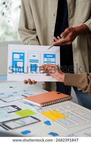 Collaborative UI UX Design. Team analyzing mobile app wireframes and layouts.