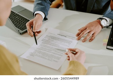 Collaborative work setting in office with people signing business document with laptop and other office supplies. Visible documents capture business focus without cluttering space