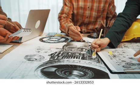 A collaborative workspace with hands working on engineering designs, featuring sketches, a laptop, tools, and technical drawings, showcasing creativity and teamwork. SACTR