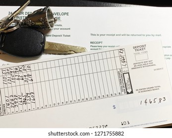 A Collage Of Bank Deposit Slip With Written Numbers And A Deposit Envelope With Car Keys On A Pewter Bell Keychain.