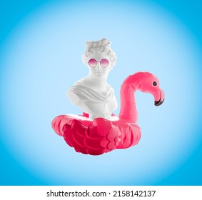 Collage of female head statuette with  inflatable flamingo and  pink glasses on  blue background. Summer travel poster concept.