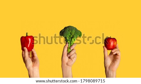 Collage with male hands holding broccoli, bell pepper and apple on orange background, close up. Panorama