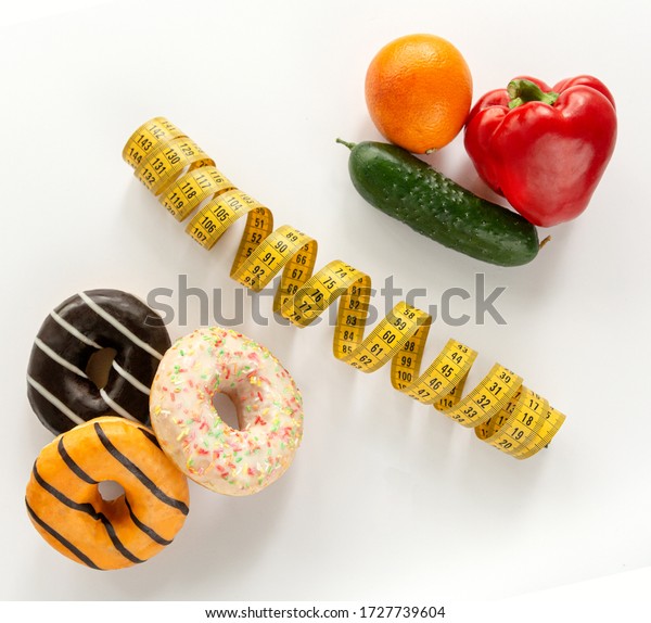 A collage of unhealthy and healthy food\
located on a white background. Food is divided by a measuring tape.\
Junk food leads to overweight.\

