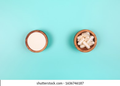 Collagen in capsules and in powder in two wooden bowls on pastel blue background