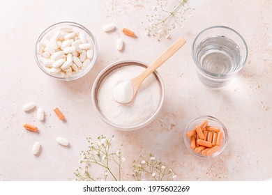 Collagen powder, pills and glass of water on beige stone table top