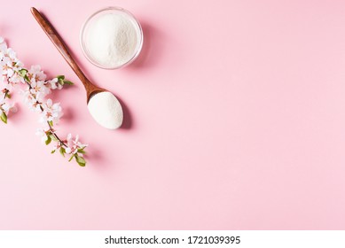 Collagen powder in wooden spoon, supplement, healthy and anti age concept flat lay on pink background, top view