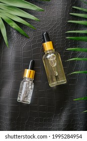 Collagen Serum Or Hyaluronic Serum In Dropper On Black Color Crocodile Skin Texture Background With Palm Leaves. Skincare Cosmetic Product Bottle. Cosmetics Health Face Skin Beauty Vertical