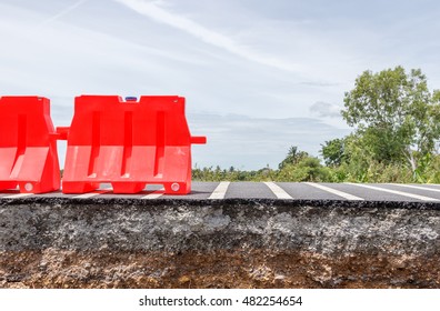 Collapsed Asphalt Road Cracked And Broken With Red Barrier.