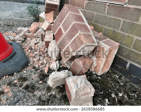 Collapsed brick wall, brick rubble visible with traffic cone