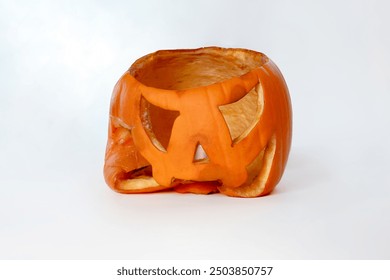 A collapsed Jack-o'-lantern with a deteriorating face on a white background, end of season