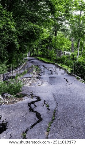 Collapsing bumpy asphalt road in need of repair, potholed road