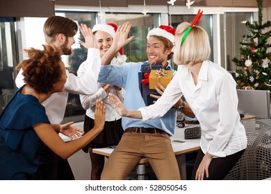 Colleagues Celebrating Christmas Party In Office Smiling Giving Presents.