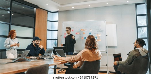 Colleagues collaborate in a boardroom. Business men and women share ideas, work on projects, and demonstrate leadership. This creative team is focused on project management and software development. - Powered by Shutterstock