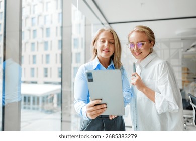 Colleagues collaborating and smiling while using a tablet in an office
