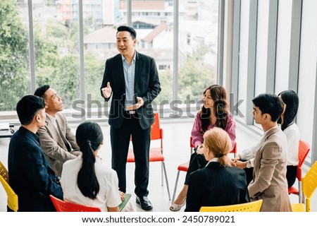 Colleagues from different backgrounds work and discuss in a modern office. They're presenting and brainstorming, highlighting teamwork, leadership, and togetherness in a business meeting.