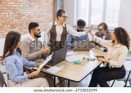 Colleagues from different generations and backgrounds achieving shared goals, showing synergy and winning spirit in a modern workspace
